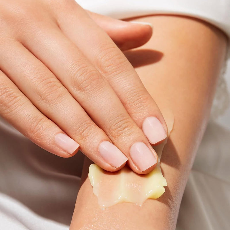 Close-up of a hand applying balm to arm with a soft focus background