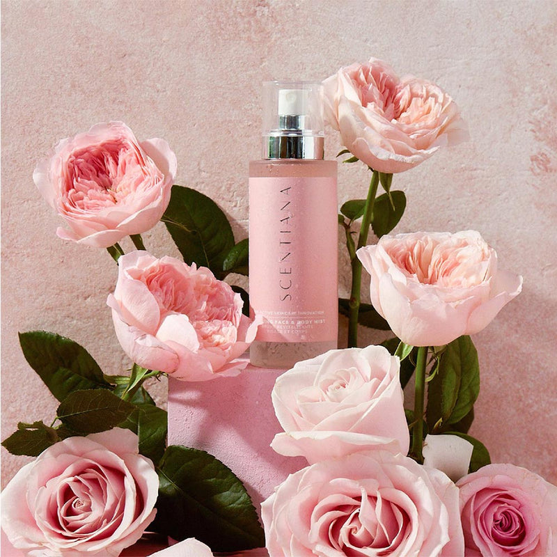 Pink bottle of Scentlana rose mist surrounded by pink roses on a pink background