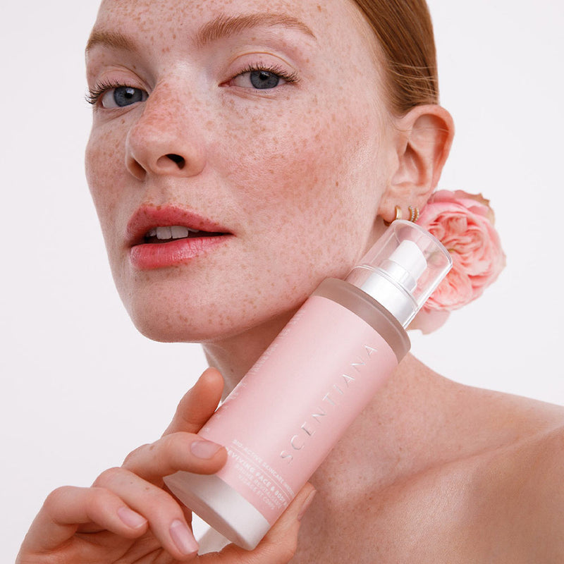 Woman holding a pink rose mist bottle with a white background
