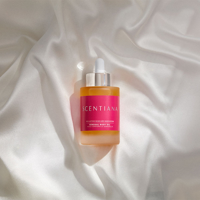 Scentiana body oil dropper bottle on white silken sheets